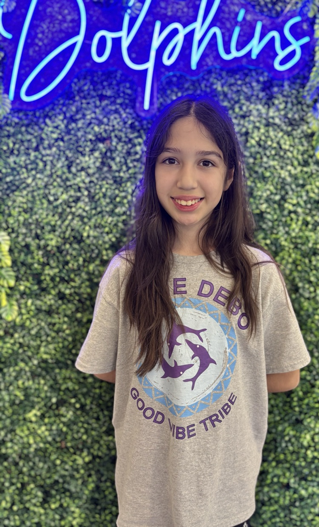 student in front of green backdrop with neon sign