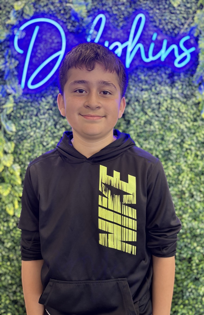 student in front of green backdrop with neon sign
