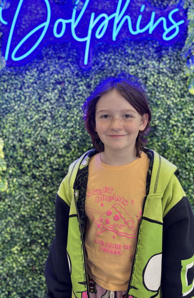 student in front of green backdrop with neon sign