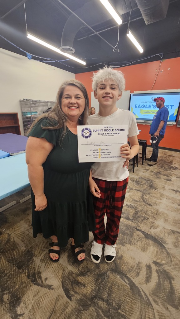 Student stands next to parent as they both smile for the camera.
