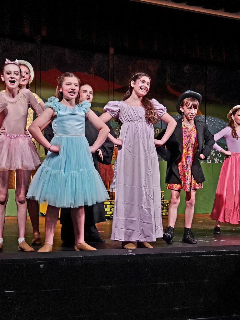 A group of students in dresses dancing on a stage
