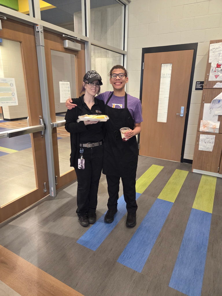 An intern and cafeteria staff with a food tray.