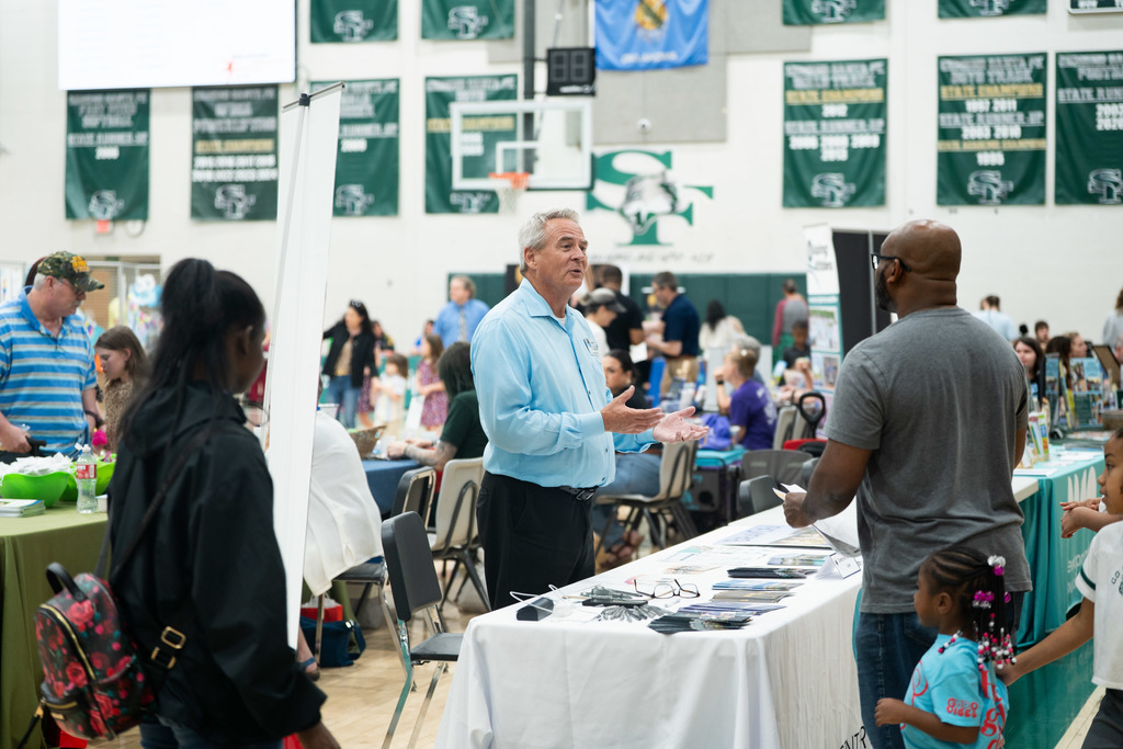 rep from a company talking at a booth to a family