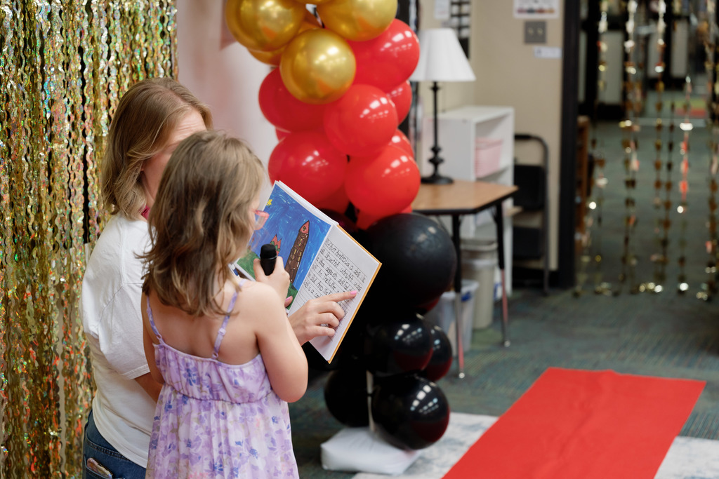 teacher helping a student read a book