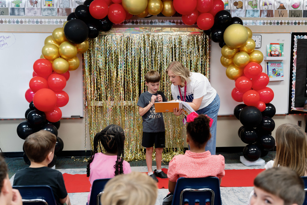 teacher helping a student read a book