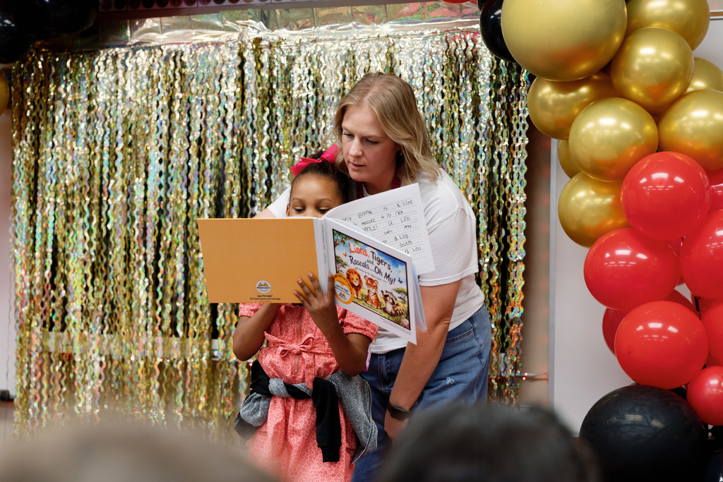 teacher helping a student read a book