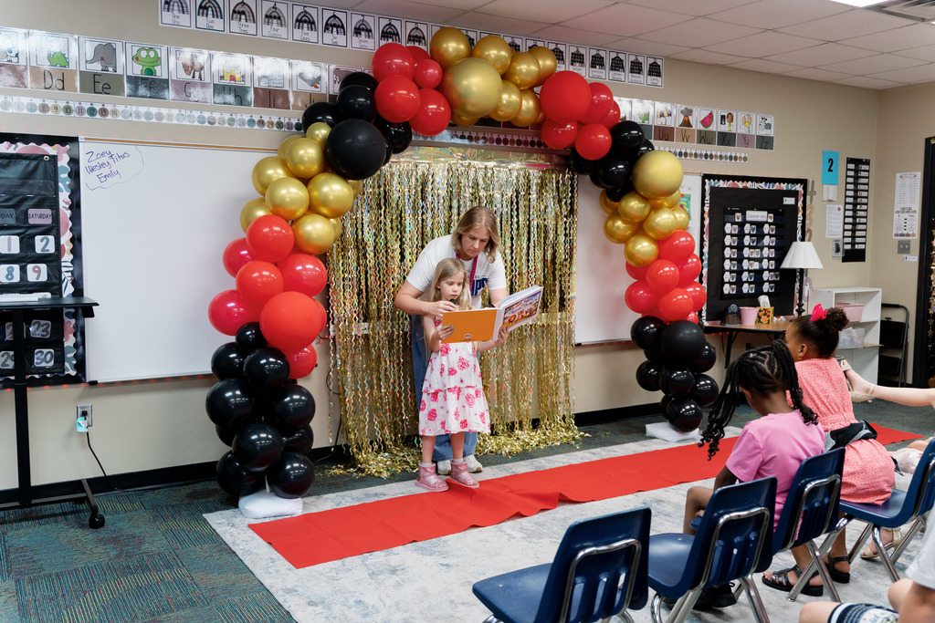 teacher helping a student read a book