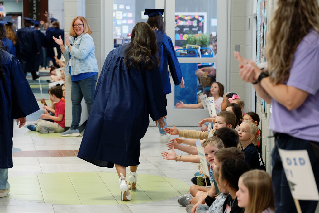 grad high fiving an elementary student