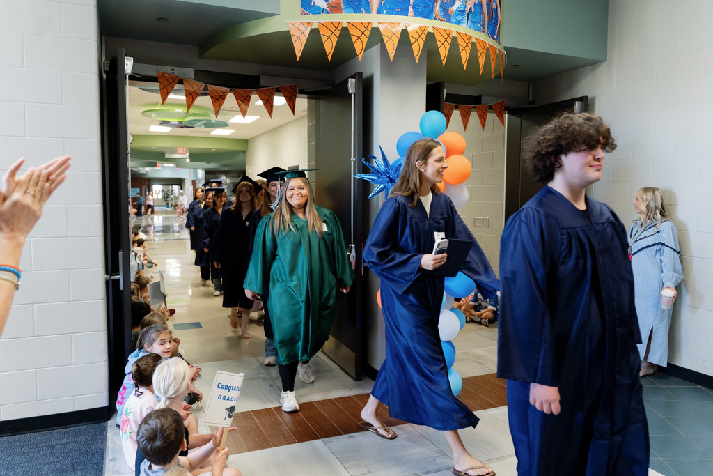students walking halls with caps and gowns