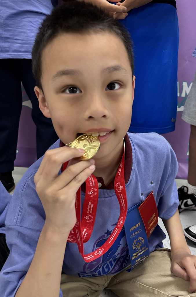 student biting on gold medal 