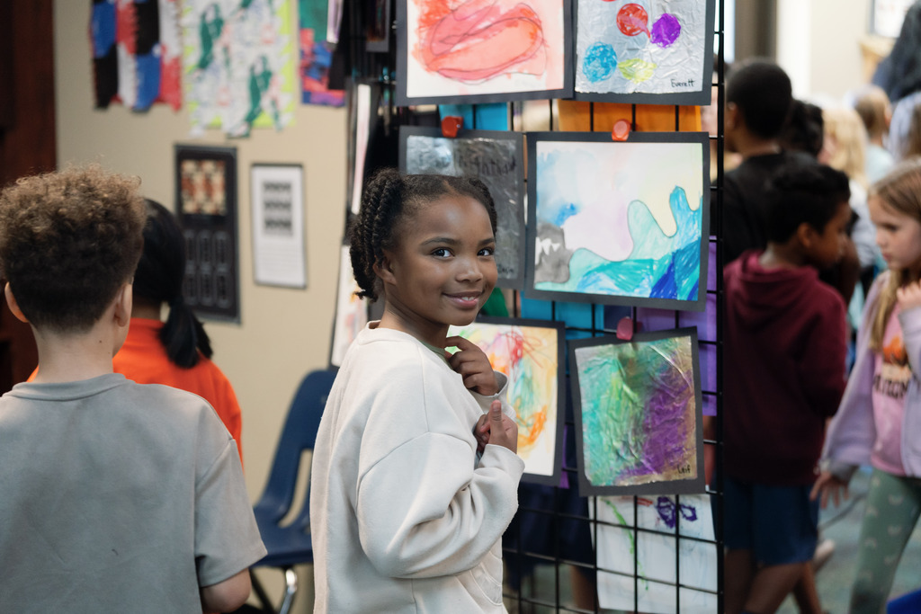 student smiling next to art