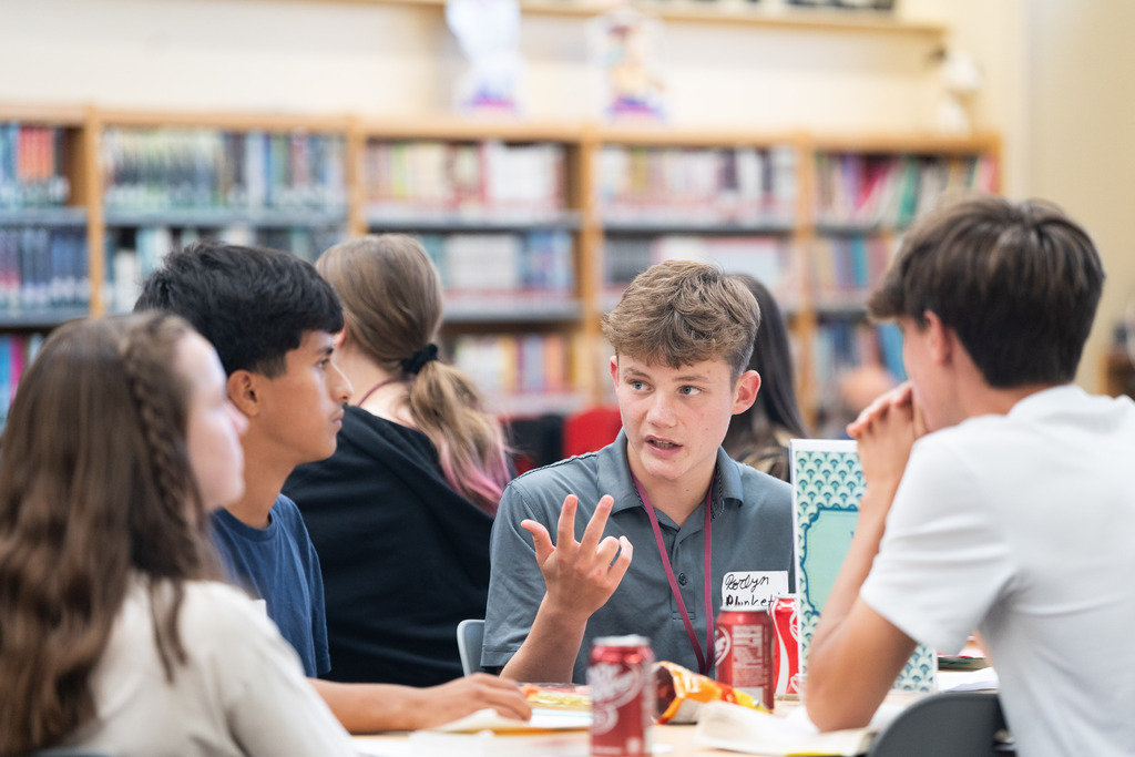 students talking at a table about a book