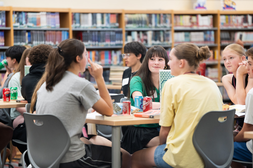 students talking at a table about a book