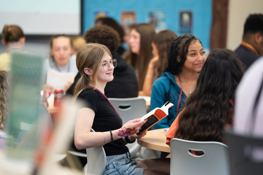 girl holding a book listening to people talk