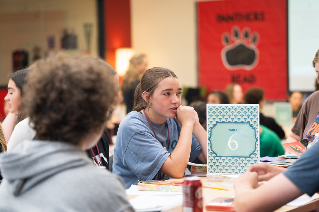 students talking at a table about a book