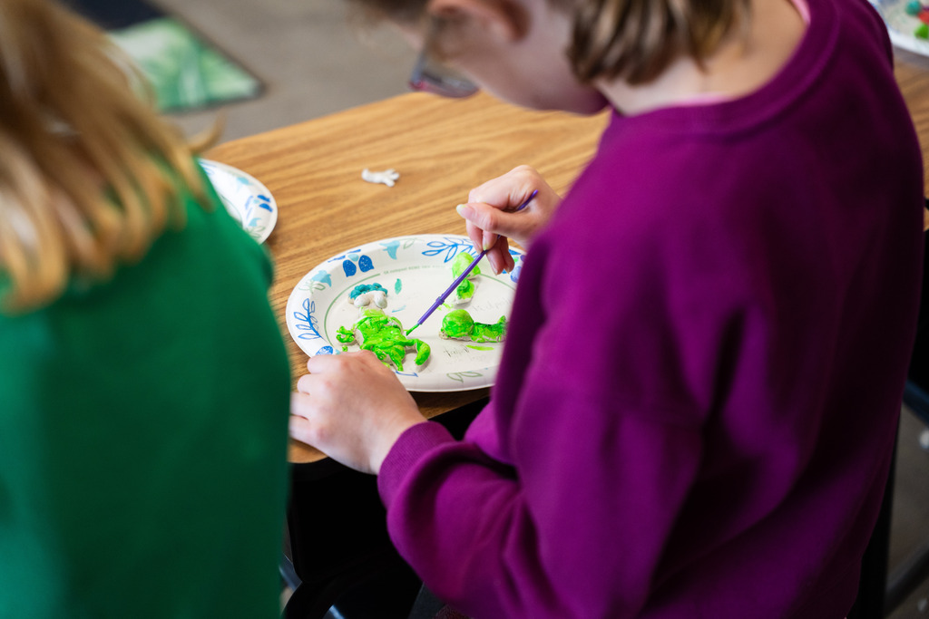 student painting a clay mold of an animal
