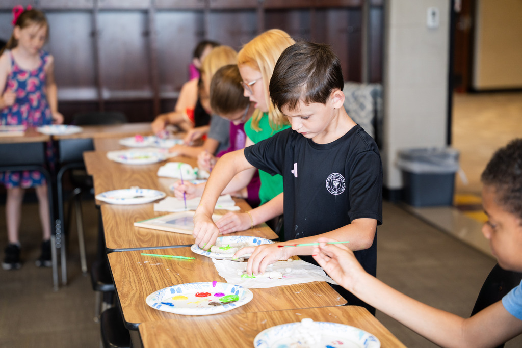 student painting a clay mold of an animal