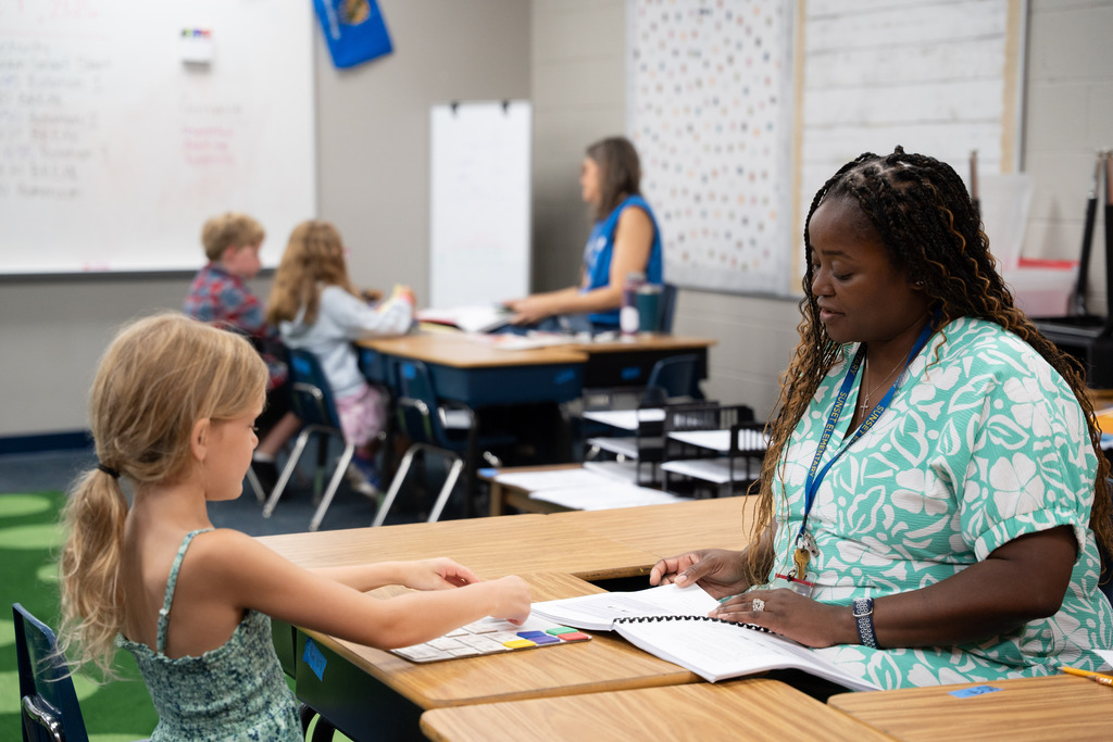 teacher and students sitting at a table working on an assignment together