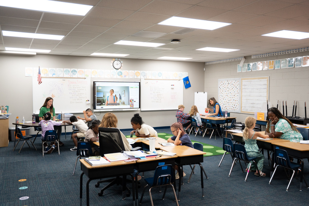 teacher and students sitting at a table working on an assignment together