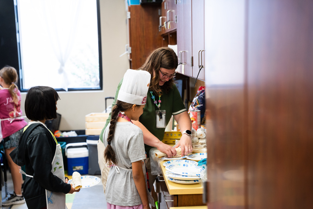 students in chef outfits and hats taking a cooking class