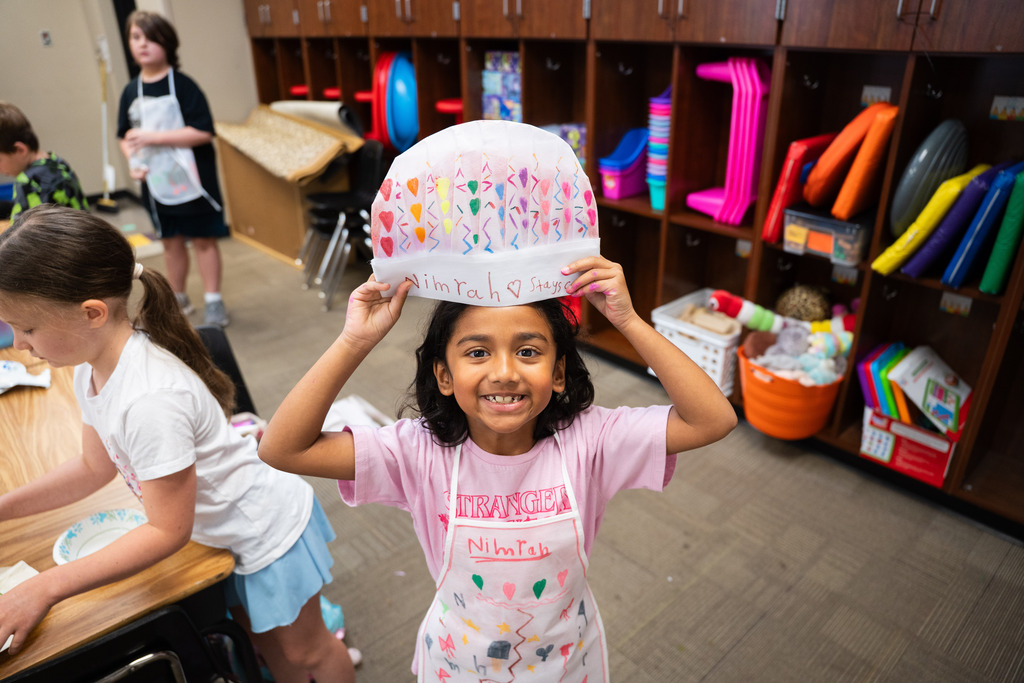 girl holding up a chef hat