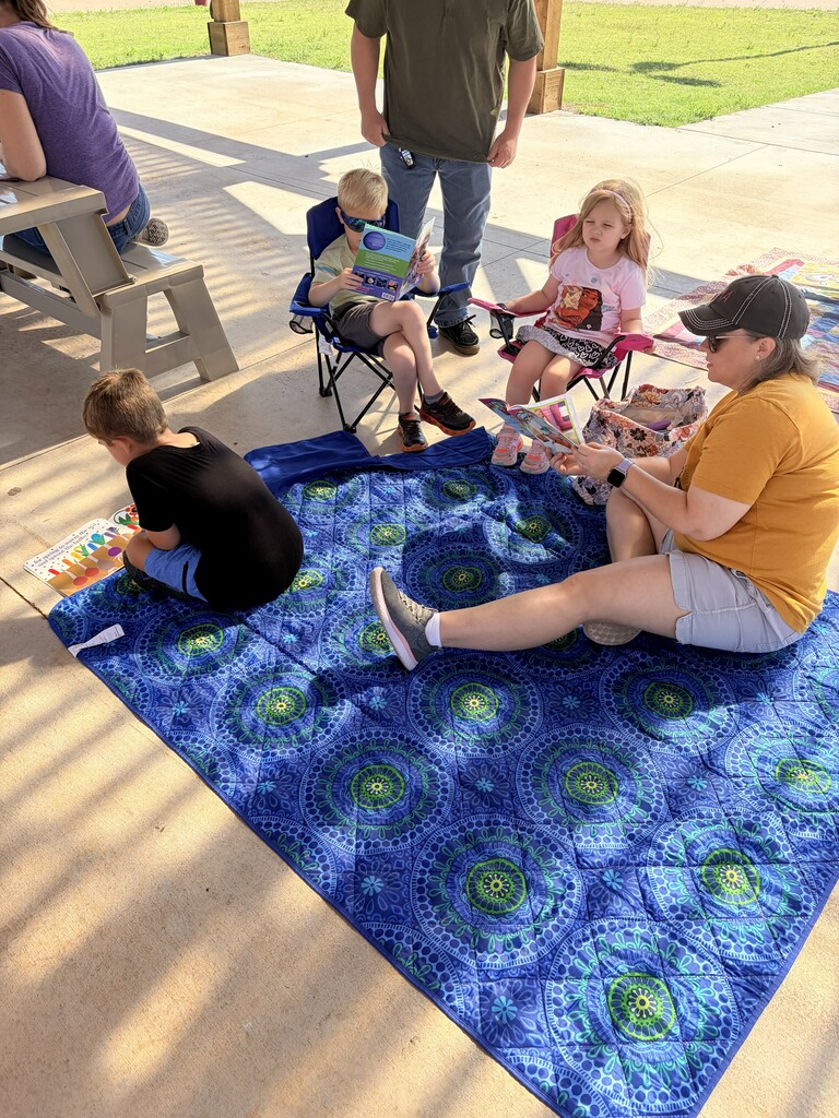 Students/parents/teachers reading at Books & Buddies summer event.