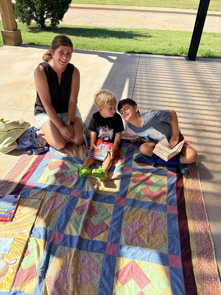 Students/parents/teachers reading at Books & Buddies summer event.