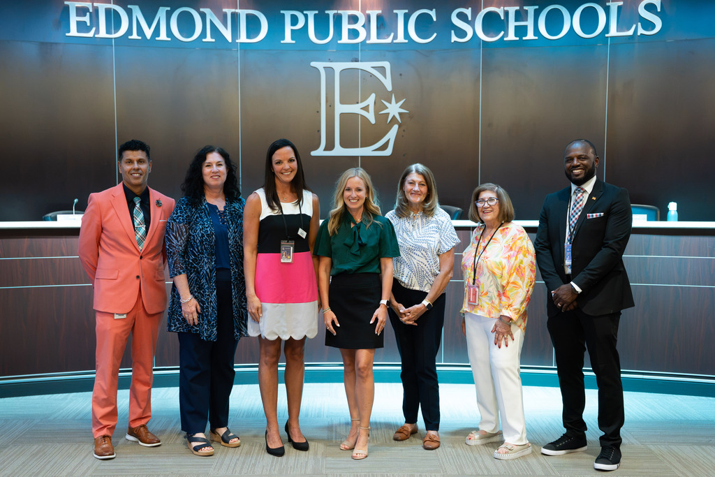 new director standing with board of education and superintendent