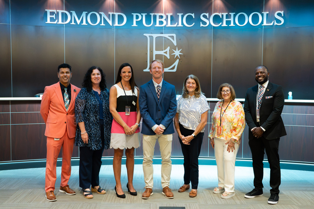 new director standing with board of education and superintendent