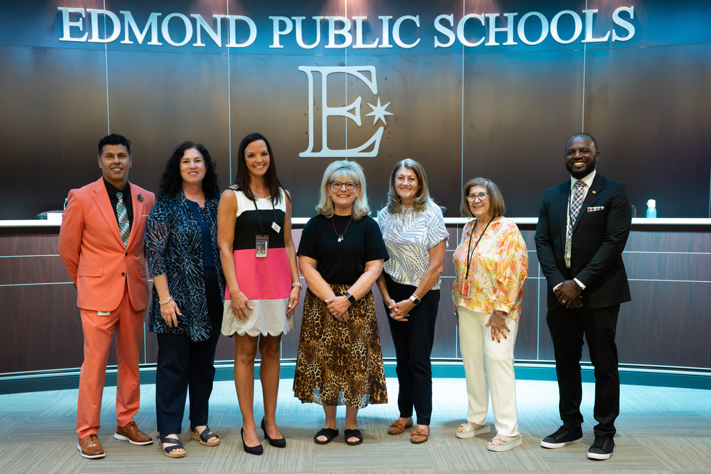 new director standing with board of education and superintendent