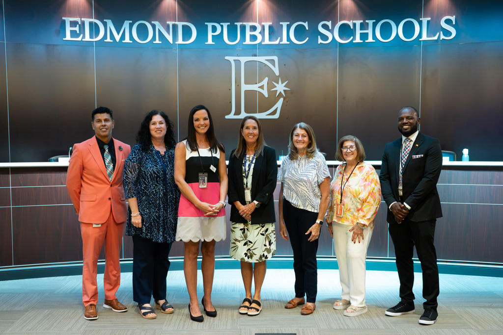 new director standing with board of education and superintendent