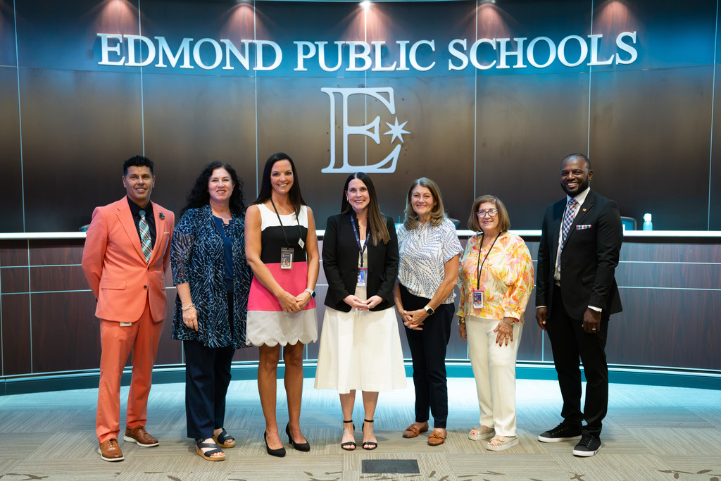 new director standing with board of education and superintendent
