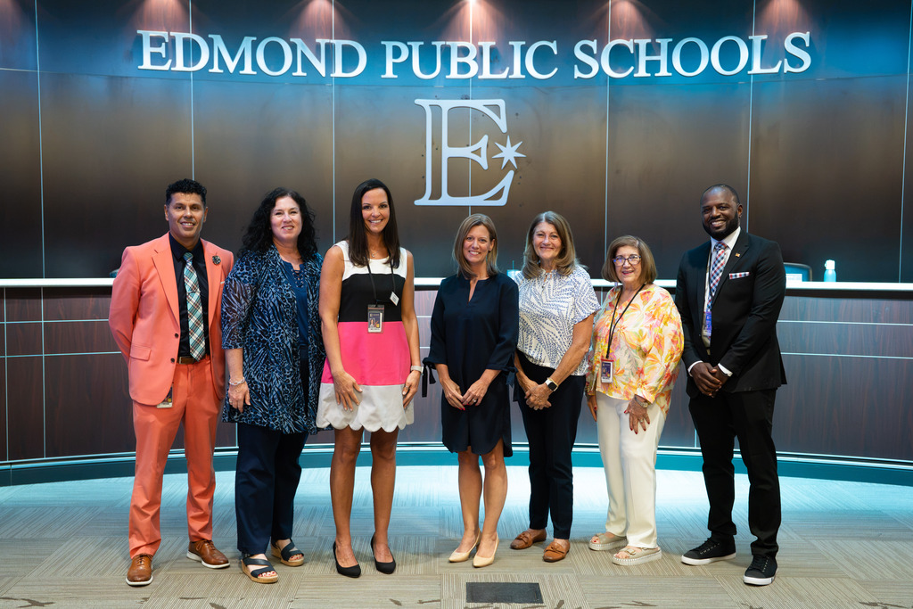 new director standing with board of education and superintendent