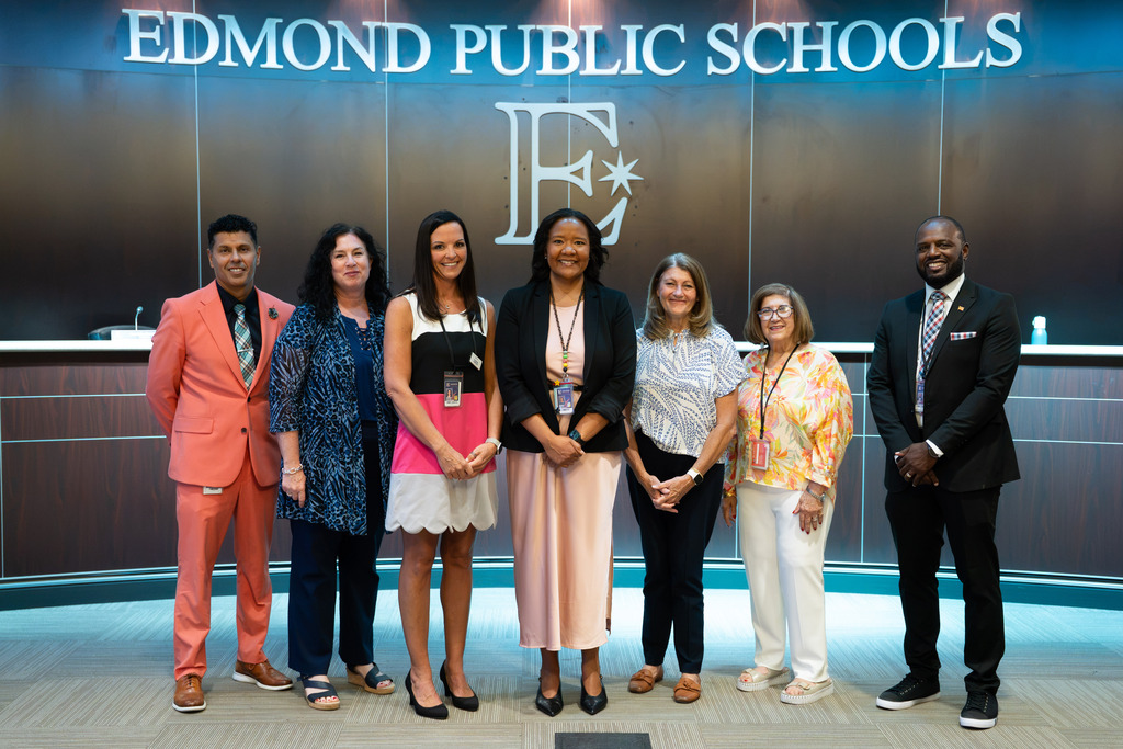 new director standing with board of education and superintendent