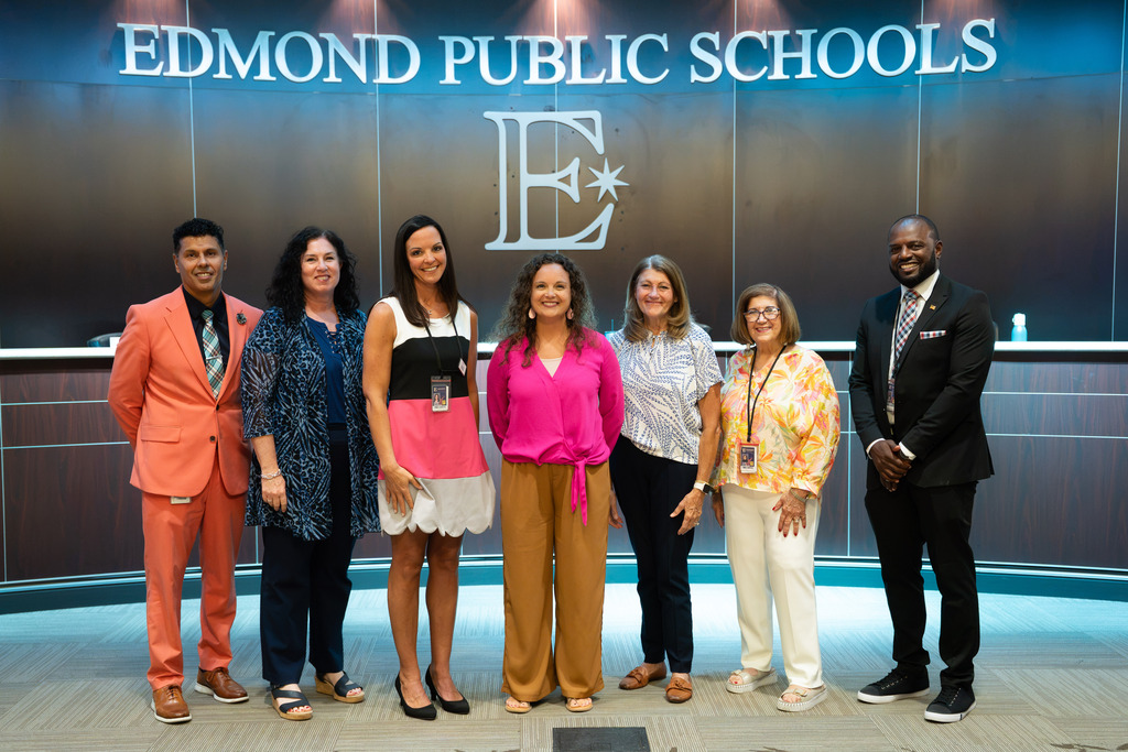 new director standing with board of education and superintendent