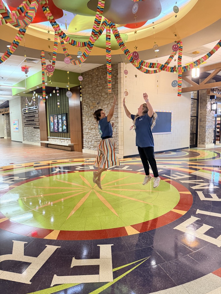 Two teachers high-fiving in the hallway.