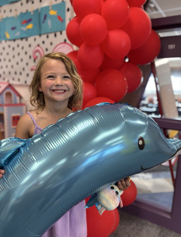 student holding dolphin balloon smiling 