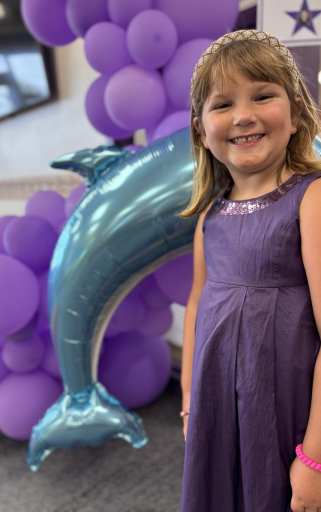 student in front of purple balloons 