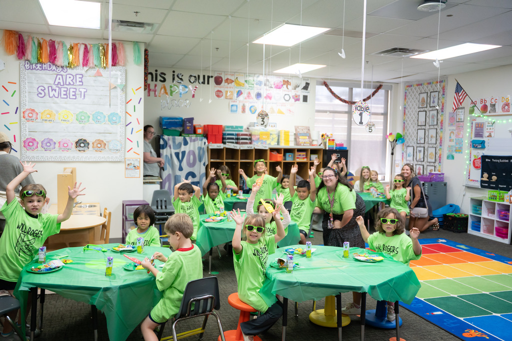 students raising their hands and smiling