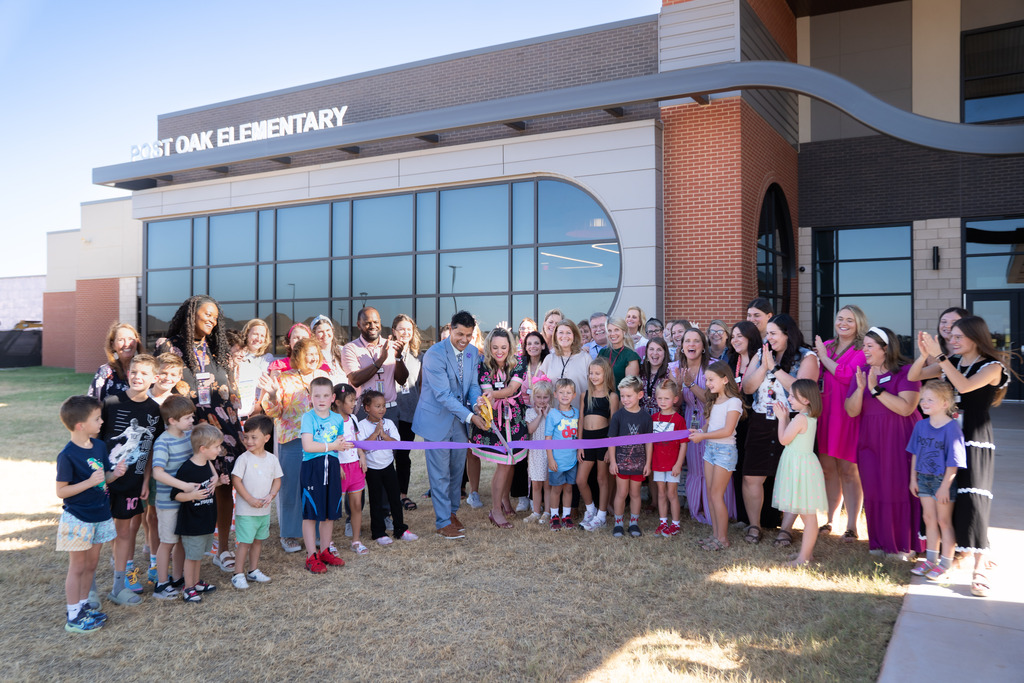 students teachers and administrators gathered in front of the school to cut a ribbon