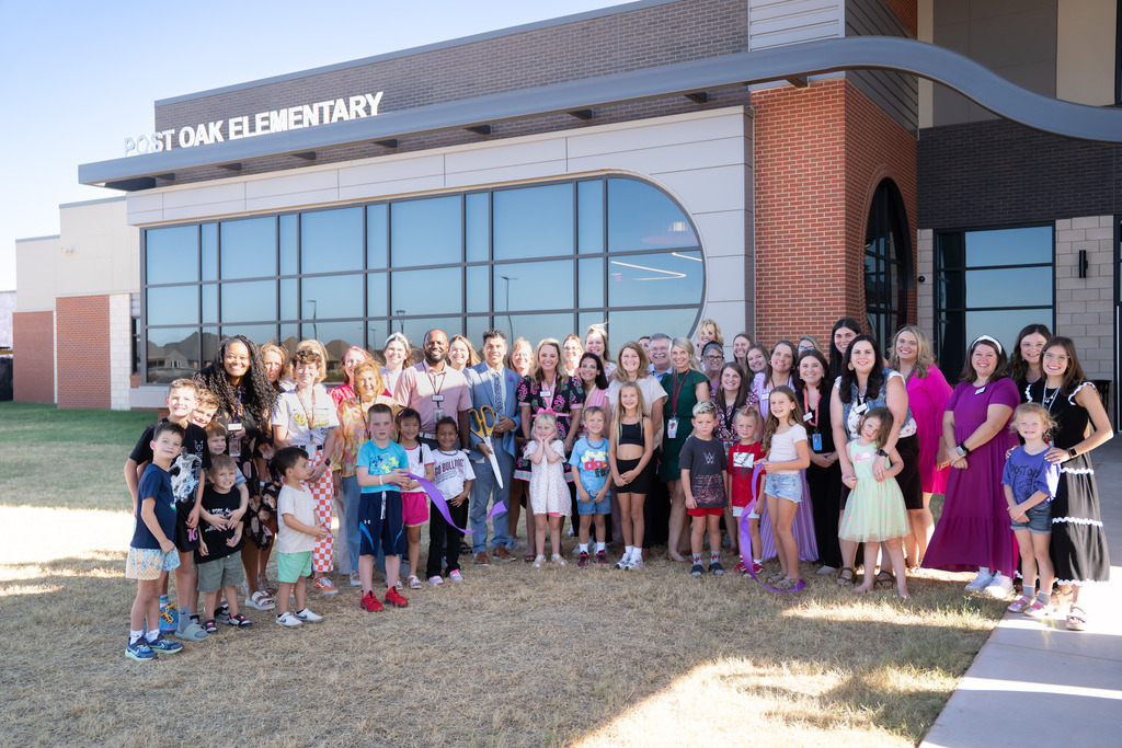 students teachers and administrators gathered in front of the school to cut a ribbon
