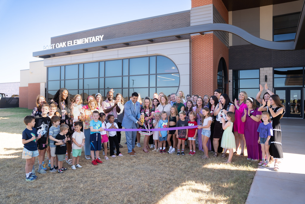 students teachers and administrators gathered in front of the school to cut a ribbon