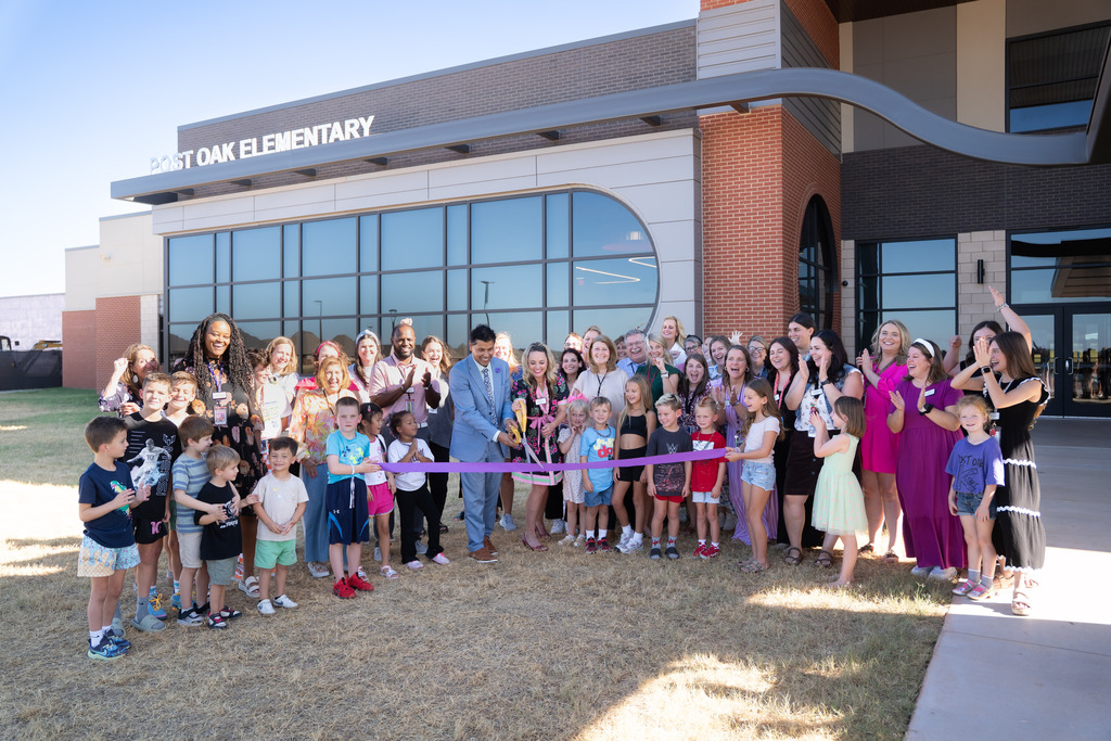 students teachers and administrators gathered in front of the school to cut a ribbon