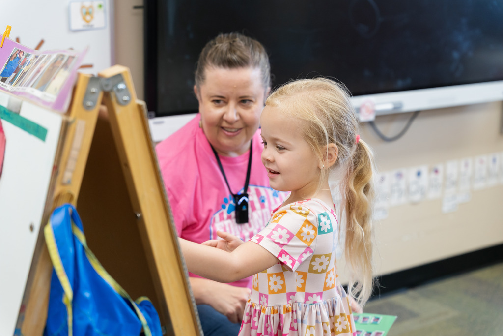 student putting her magnet on a white board