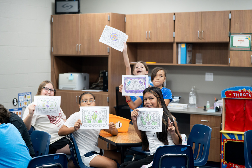 students holding up their artwork