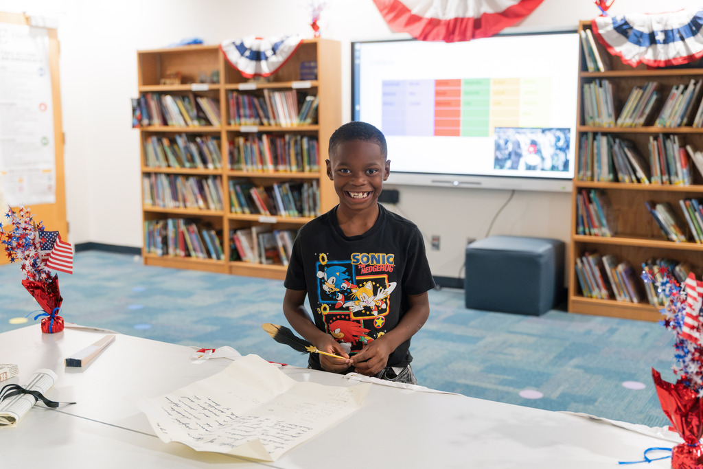student signing a replica constitution and smiling