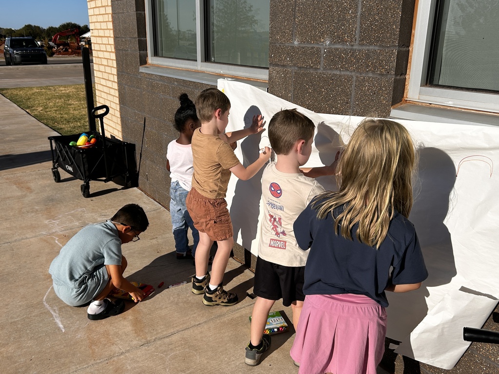 Kindergarten students drawing with friends outside.