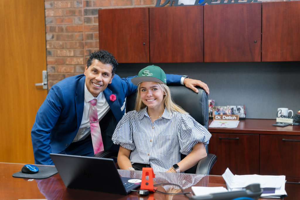 student posing at superintendent's desk with superintendent