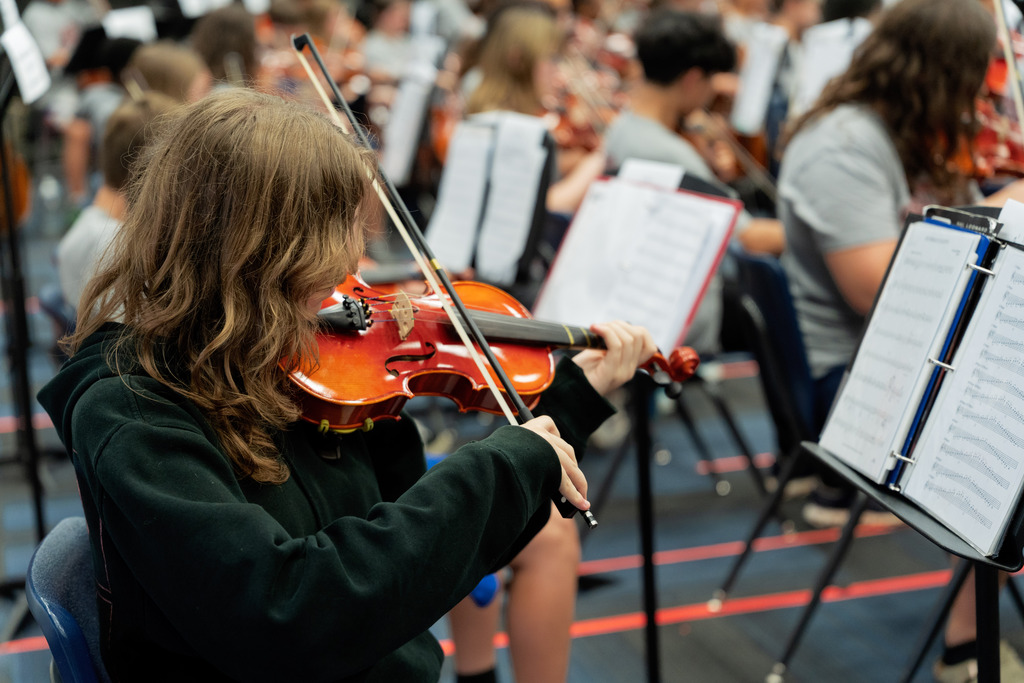 middle school student playing instrument in large band room