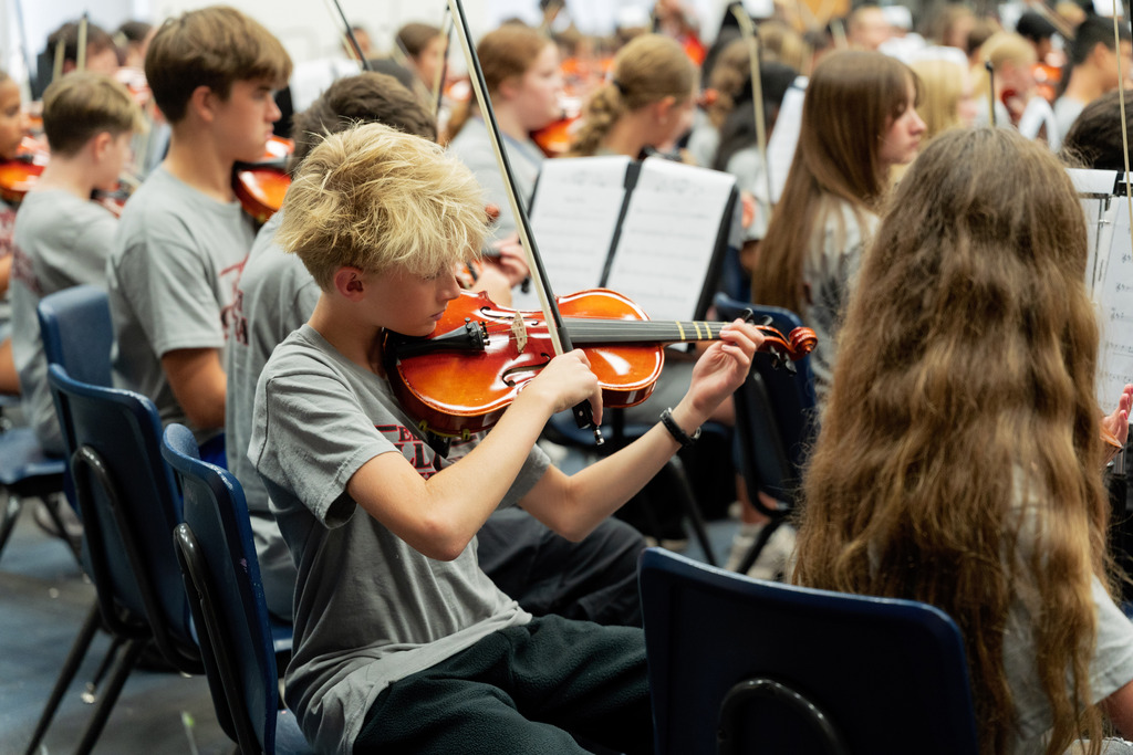 middle school student playing instrument in large band room